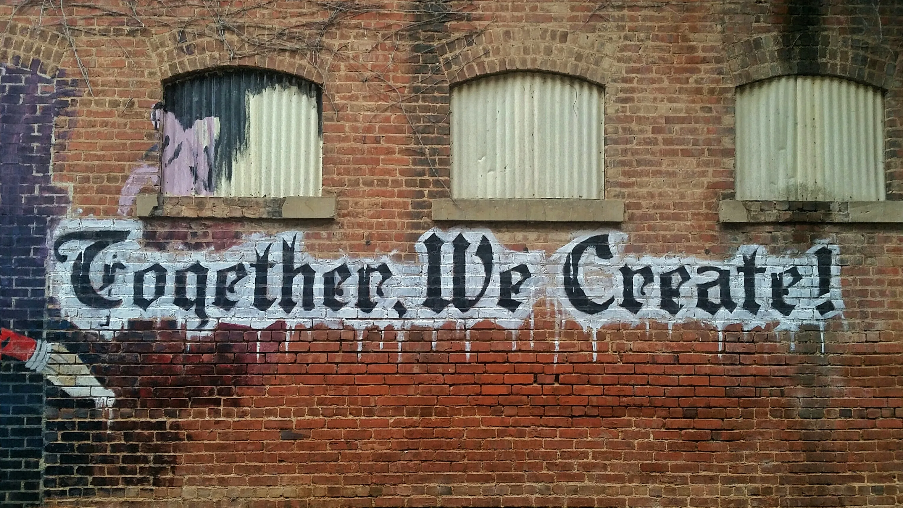 A brick wall with graffiti that says 'together we create!'